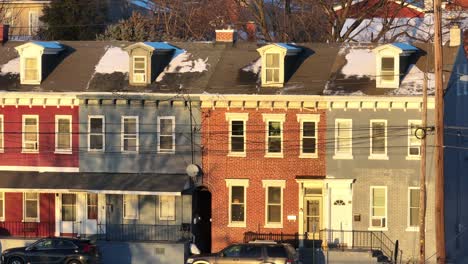 Aerial-zoom-of-colorful-houses-lighting-at-sunset-during-winter-time