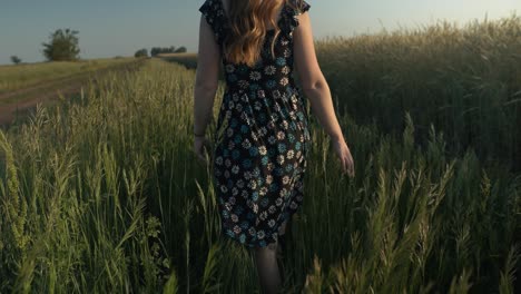Young-woman-walking,-enjoying-the-calm,-peaceful-and-serene-summer-sunset-with-light-shining-on-her-hair-during-golden-hour-in-cinematic-slow-motion