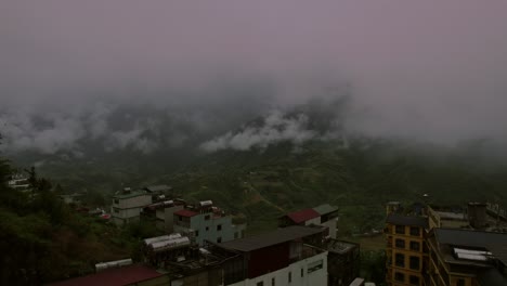 Misty-mountain-town-to-terraced-rice-fields-in-Sapa,-Vietnam---aerial