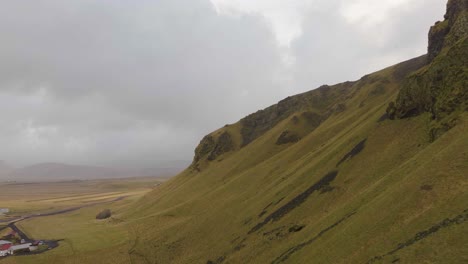 Majestic-drone-footage-of-an-Icelandic-Cliffside-with-a-vast-field-in-the-background