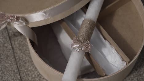 Close-up-of-a-decorative-box-with-a-baptismal-candle-and-ribbon-on-a-textured-stone-surface