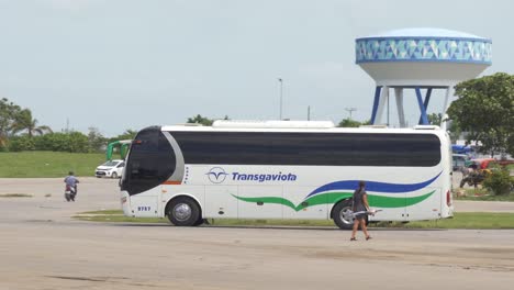 Chinese-Yutong-ZK6107HA-bus-of-Transgaviota-public-transportation-company-in-Cuba,-panning-shot-at-bus-station-on-old-airport