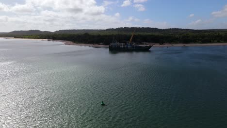 Aerial-orbital-clip-of-a-container-barge-docked-in-calm-remote-waters-in-northern-Australia