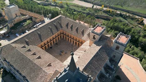 ascending-flight-in-the-Monastery-of-Uclés-visualizing-the-cloister-with-its-arches,-the-roof-of-the-church-with-its-entrance-towers-and-the-head-of-another-tower-topped-with-a-dark-pointed-tip