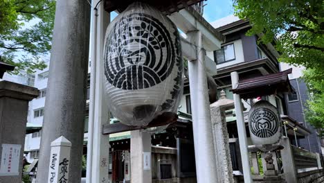 Japanese-temple-entrance-with-traditional-lanterns-and-inscriptions,-surrounded-by-greenery