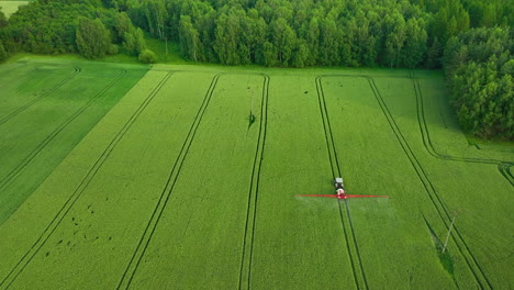 Luftaufnahme-Eines-Grünen-Feldes-Mit-Einem-Traktor,-Der-In-Der-Nähe-Eines-Dichten-Waldes-Arbeitet