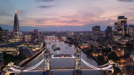 Twilight-drone-pullback-over-Thames-with-Tower-Bridge-view-and-London-skyline