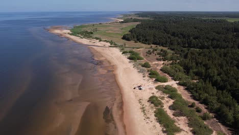 Aerial-view-of-repair-works-along-the-Baltic-Sea-coast,-featuring-visible-construction-machinery-and-a-concrete-footbridge