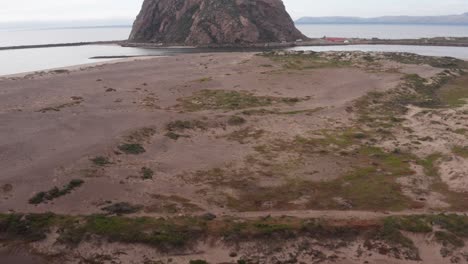 Niedrige,-Nach-Oben-Geneigte-Luftaufnahme-Von-Morro-Rock-Am-Rande-Der-Morro-Bay,-Kalifornien