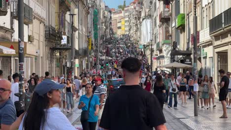 Point-of-view-of-tourists-walking-at-the-pedestrian-street-of-Rua-Santa-Catarina-shopping-and-culinary-area-during-the-celebration-of-the-festival-of-São-João-do-Porto,-Portugal