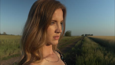 Mujer-Joven-En-La-Granja-Disfrutando-De-La-Tranquila,-Pacífica-Y-Serena-Puesta-De-Sol-De-Verano-Con-Luz-Brillando-En-Su-Cabello-Durante-La-Hora-Dorada-En-Cámara-Lenta-Cinematográfica