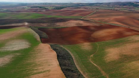 Flight-over-farmland-where-we-appreciate-a-spectacular-mix-of-colors-separated-by-agricultural-plots:-there-are-green,-brown,-black-and-red-tones,-a-visual-wonder-in-the-province-of-Cuenca