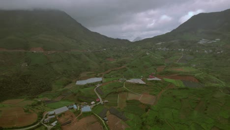 Aerial-of-Sapa's-lush-valley-and-farmlands-with-mountains-shrouded-in-mist-and-scattered-rural-structures