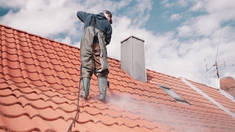 Limpieza-Profesional-De-Tejas-Con-Presión-De-Agua-Por-Un-Trabajador-Caucásico-En-Un-Traje-De-Goma-En-Alemania,-Europa-Con-Nubes-En-El-Cielo