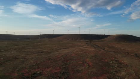 Aerial-approaching-flight-over-scenic-landscape-with-wind-turbines-on-hill