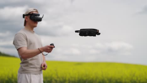 Male-fly-FPV-drone-near-blooming-rapeseed-field-and-dark-cloud-sky,-Czechia