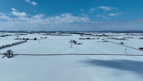 Aerial-lateral-wide-shot-of-snowy-winter-landscape-in-rural-area-at-sunny-day