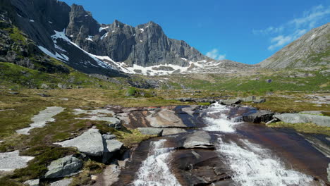 Cinematic-shot-of-the-Molneva-waterfall-and-beautiful-snowy-mountains-in-the-background