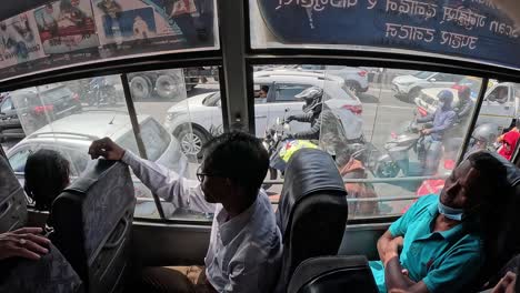 A-Nepalese-bus-on-busy-street,-Passenger-looking-outside-the-window-with-traffic-passing-by-behind-daily-life-in-Kathmandu