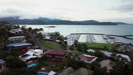 Port-Airlie-Beach-Bay-Lagoon-Coral-Sea-marina-aerial-drone-dark-rain-clouds-sunrise-morning-heart-of-Great-Barrier-Reef-Whitsundays-Whitehaven-jetty-yachts-sailboats-airbnb-buildings-upwards-motion