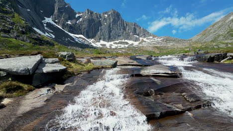 Aerial-view-touring-the-beautiful-Molneva-waterfall-and-fantastic-snow-capped-mountains-in-the-background