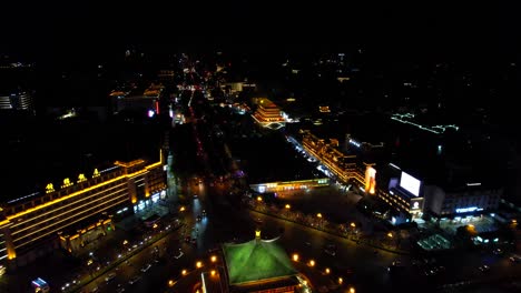 Aerial-overview-cars-in-rotary-by-Bell-and-Drum-Towers-at-nighttime-in-Xian,-China