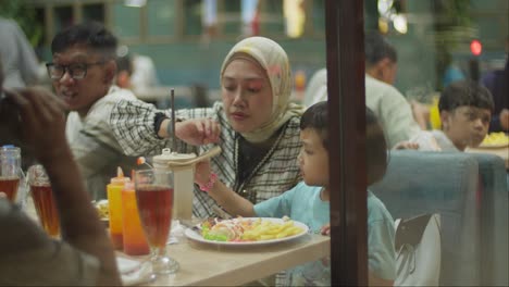 Mother-wearing-a-hijab-from-Indonesia-feeding-her-child-at-a-restaurant