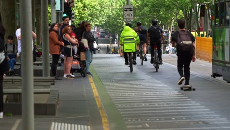 El-Tranvía-Llegó-A-La-Parada-De-Swanston-Street,-Con-Pasajeros-Esperando-Para-Subir,-Patinadores,-Ciclistas-Y-Repartidores-En-Bicicleta-Por-El-Carril,-Un-Vibrante-Estilo-De-Vida-Urbano-De-Melbourne.