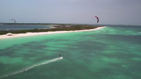 Kitesurfista-Deslizándose-Sobre-Aguas-Turquesas-Cerca-De-Una-Prístina-Playa-De-Arena-Blanca-En-Un-Día-Soleado