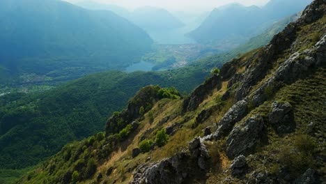 Rising-aerial-summer-alpine-lakes-between-rugged-mountain-peaks,-Lake-Como,-Italy