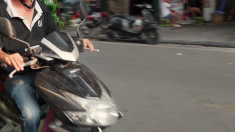 A-man-transports-green-plants-on-a-scooter-through-the-historic-O-Quan-Chu-o-ng-gate-in-Hanoi-Old-Town,-Vietnam