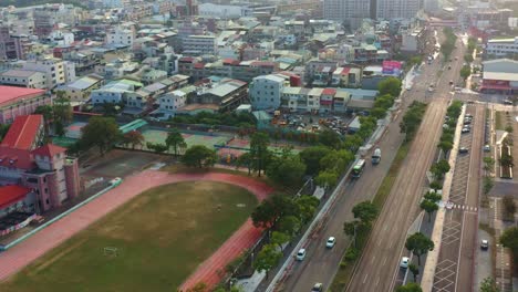 Vista-Aérea-Del-Paso-Elevado-De-Drones-Que-Captura-El-Tráfico-Callejero-En-Mingde-N-Rd,-Paisaje-Urbano-De-Douliu-Con-La-Escuela-Primaria-Gongcheng-Al-Atardecer