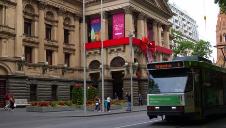 Melbourne-city-town-hall,-decorated-with-Christmas-decorations-on-the-building-facade-during-the-festive-season,-with-the-tram-running-across-the-scene-in-downtown-central-business-district