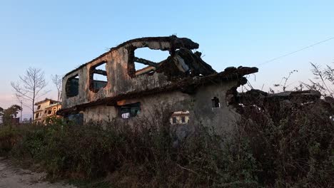 Una-Casa-En-Chisapani,-Nepal,-Está-En-Ruinas-Después-De-Un-Terremoto,-Con-Un-Hotel-Cercano-Inclinado-Por-El-Temblor.