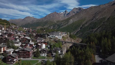 Sunny-stunning-daytime-Saastal-Saas-Fee-village-town-Switzerland-aerial-drone-beautiful-Fall-Autumn-Swiss-Alps-mountain-peaks-glacier-surrounding-city-buildings-Zermatt-The-Matterhorn-forward-reveal