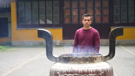 Man-near-garge-incense-burner-in-Chinese-temple-courtyard