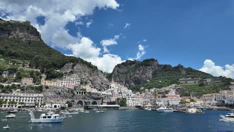 Dynamic-Timelapse-at-Marina-Coppola-in-Amalfi-Harbor-with-fast-moving-clouds,-majestic-mountains,-and-the-Amalfi-Coast,-Italy