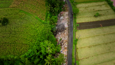 Montones-De-Basura-Arrojados-Junto-A-Una-Carretera-Rural-Entre-Exuberantes-Tierras-Agrícolas,-Drones