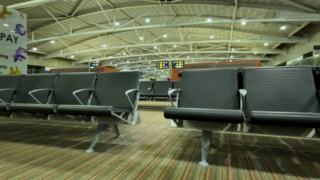 Empty-seating-area-in-Larnaca-Airport,-Cyprus,-with-modern-design-and-illuminated-signage-in-the-background