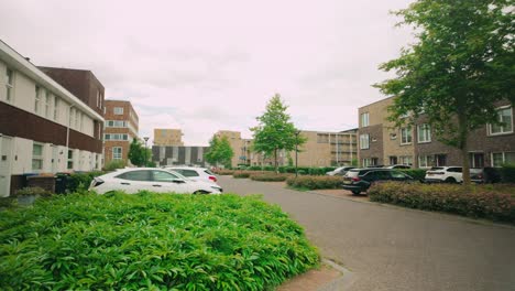 Footage-of-a-serene-Lelystad-street-lined-with-parked-cars,-houses,-and-verdant-green-bushes-and-trees,-capturing-the-essence-of-suburban-tranquility-in-the-Netherlands