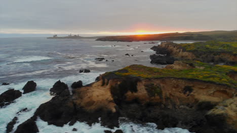 Beautiful-Central-California-ocean-cliffs,-drone-sweeps-right-to-reveal-majestic-elephant-seals-nesting-in-cove-rookery-at-sunset-near-San-Simeon,-Hearst-Castle,-Highway-1,-Cambria,-4k-Pro-Res-422-HQ