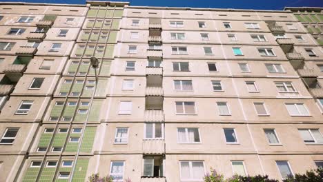 Footage-shows-a-low-angle-view-of-a-high-rise-concrete-Khrushchevka-apartment-block-on-a-sunny-day,-highlighting-its-utilitarian-design-and-historical-significance