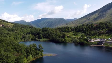 Drohnenaufnahmen-Fangen-Die-Ruhige-Schönheit-Des-Blue-Eye-Lake-In-Albanien-Ein,-Umgeben-Von-üppigen-Grünen-Hügeln-Und-Majestätischen-Bergen-Unter-Einem-Klaren-Blauen-Himmel