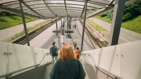 Female-and-others-descending-modern-stairs-of-Noorderpark-metro-station,-arriving-at-the-platform-in-Amsterdam