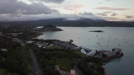 Port-Airlie-Beach-Bay-Lagoon-Coral-Sea-marina-aerial-drone-raining-dark-cloudy-sunrise-morning-heart-of-Great-Barrier-Reef-Whitsundays-Whitehaven-jetty-yachts-sailboats-buildings-forward-motion