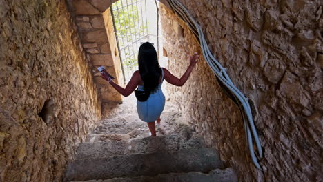 Attractive-young-female-walking-down-the-stairs-in-an-ancient-castle