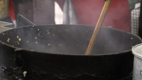 Kettle-Corn-Being-Cooked-And-Stirred-With-Wooden-Spoon-In-Large-Pot-At-50th-Dogwood-Festival-In-Siloam-Springs,-Arkansas