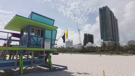 Pan-shot-from-Miami-beach-modern-building-to-lifeguard-tower-on-sand-beach,-Florida