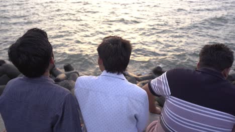 Eine-Gruppe-Junger-Männer-Sitzt-Abends-Am-Ufer-Mit-Blick-Auf-Das-Meer-Am-Marine-Drive-Beach