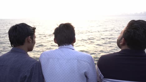 Group-of-young-men-looking-at-the-sea,-Marine-Drive-beach